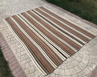 May include: A striped rug with brown, white, and gray stripes. The rug is made of wool and has a hand-woven texture.