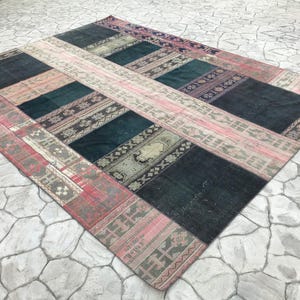 May include: A patchwork rug with a variety of colors and patterns, including pink, red, green, and black. The rug is made of woven fabric and has a distressed, vintage look.