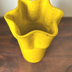 Puede incluir: Un jarr&oacute;n de cer&aacute;mica amarillo brillante con un borde &uacute;nico en forma de estrella. El jarr&oacute;n tiene una superficie texturizada y un aspecto ligeramente desgastado, lo que aumenta su encanto r&uacute;stico. El jarr&oacute;n mide unos 18 cm de alto.