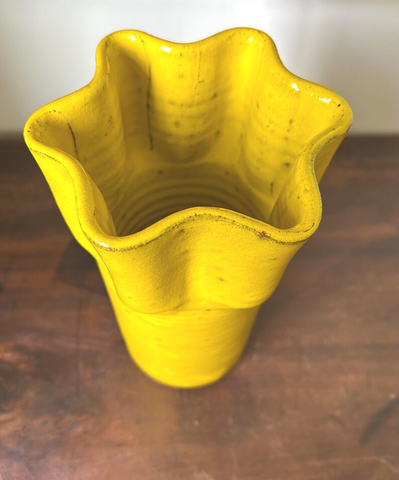 Puede incluir: Un jarr&oacute;n de cer&aacute;mica amarillo brillante con un borde &uacute;nico en forma de estrella. El jarr&oacute;n tiene una superficie texturizada y un aspecto ligeramente desgastado, lo que aumenta su encanto r&uacute;stico. El jarr&oacute;n mide unos 18 cm de alto.