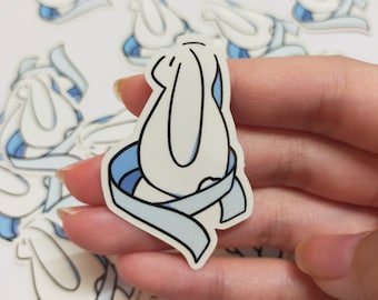 May include: A white bunny rabbit sticker with a blue scarf wrapped around it. The sticker is on a white background.