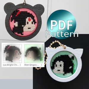 May include: Two cross-stitch keychains featuring anime characters. The first keychain is a black and pink bear with a cross-stitch image of a girl with black hair and a red bow. The second keychain is a white cat with a green cross-stitch image of a girl with black hair. The text "PDF Pattern" is visible in the image.