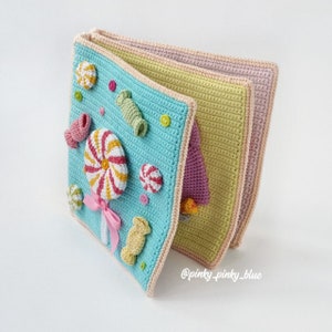 May include: A crocheted baby book with colorful candy and lollipop appliques. The book has multiple pages and is made with a variety of textures. The book is a great way to stimulate a baby's senses.