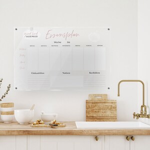 Könnte beinhalten: Eine transparente Essensplan-Tafel aus Acryl mit den Worten "good food GOOD MOOD" und "Essensplan" in rosa Schrift. Die Tafel hat Abschnitte für jeden Wochentag, eine Einkaufsliste, Notizen und Kochideen.
