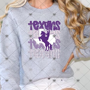 May include: A heather gray crewneck sweatshirt featuring a graphic print with the word "texans" repeated four times in varying purple and white patterns. A silhouette of a cowboy riding a bucking horse is centered over a white map of Texas.