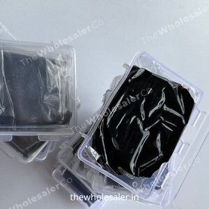 May include: Multiple clear plastic containers stacked on top of each other. Each container holds a black, rectangular object wrapped in plastic.