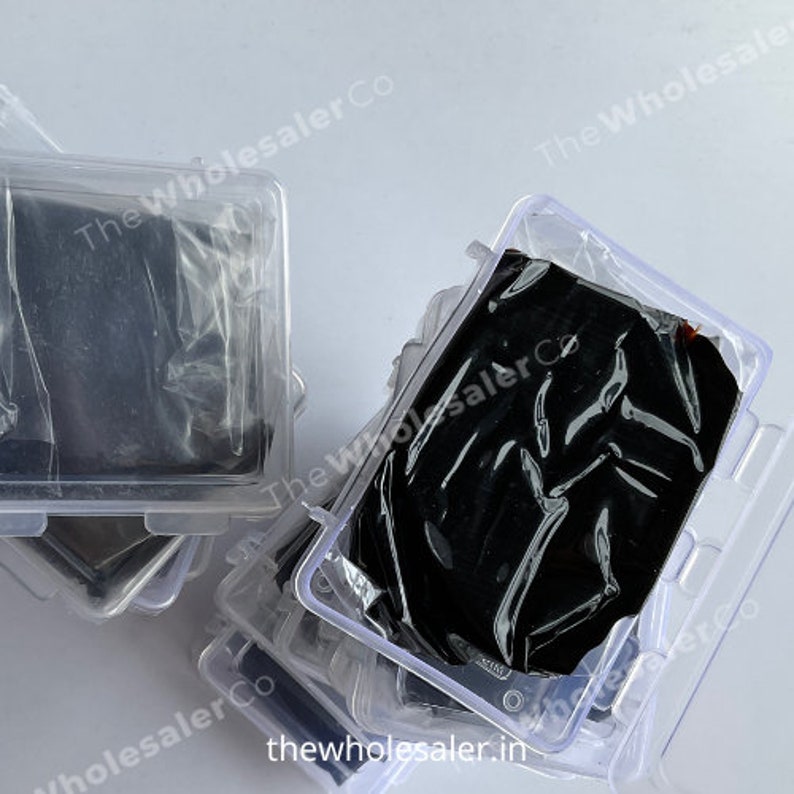 May include: Multiple clear plastic containers stacked on top of each other. Each container holds a black, rectangular object wrapped in plastic.