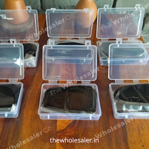 May include: Six clear plastic containers with lids, each containing a black, rectangular object. The containers are arranged in two rows of three. The text "The Wholesaler Co" is visible on the containers.