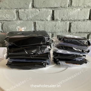 May include: A stack of five black rectangular blocks wrapped in clear plastic, and a stack of six black rectangular blocks wrapped in clear plastic. The blocks are on a white surface.