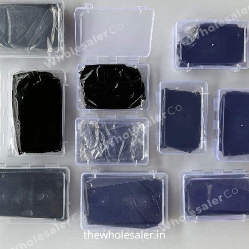 May include: Multiple clear plastic boxes with black fabric squares inside. The boxes are arranged in a grid pattern on a white surface. The text "thewholesaler.in" is visible on the bottom of the image.