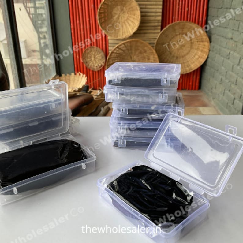 May include: Multiple clear plastic storage boxes with black lids. The boxes are stacked on top of each other. The boxes are empty.