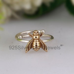 May include: A silver ring with a gold bee charm. The ring is adjustable and has a simple design.