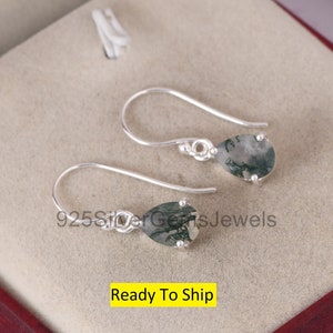 May include: A pair of silver dangle earrings with pear-shaped green moss agate stones. The earrings are ready to ship.
