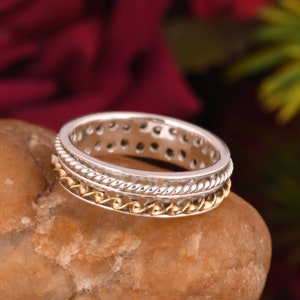 Peut inclure: Une bague en argent et or avec un design torsadé. La bague est composée de trois bandes, une en argent, une en or et une en argent avec une texture en forme de corde.