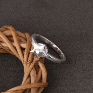 Puede incluir: Un anillo de plata con un diseño en forma de estrella. La estrella tiene un corazón en el centro.