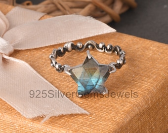 May include: A silver ring featuring a blue and green star-shaped gemstone. The ring has a delicate, ornate design.