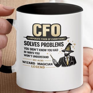 May include: White ceramic mug with a black interior and handle. The mug features the text "CFO (Corporate Fixer of Everything)" and a graphic of a wizard. The mug also says "Solves Problems" and "Wizard - Magician - Legend".