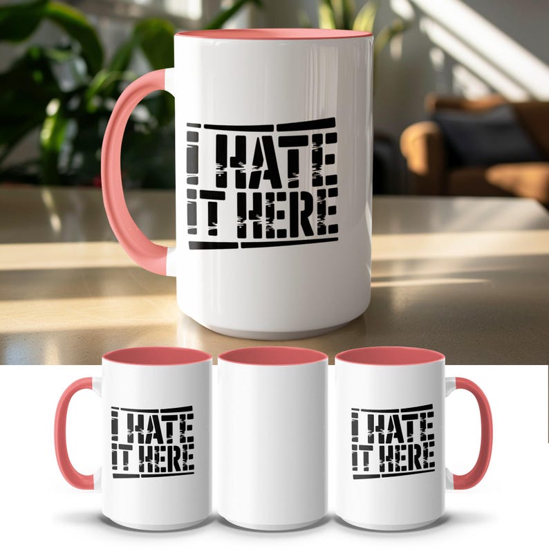 White mug with coral handle, "I HATE IT HERE" in black text.