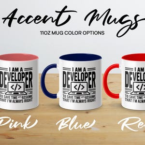 Three 11oz mugs with "I AM A DEVELOPER" text in pink, blue, and red.