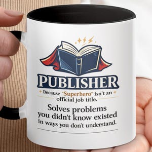Peut inclure: Mug en céramique blanche avec une anse et un intérieur noirs. Le mug présente le mot "PUBLISHER" au-dessus d'une illustration d'un livre ouvert avec une cape. Le texte en dessous indique "Because 'Superhero' isn't an official job title."