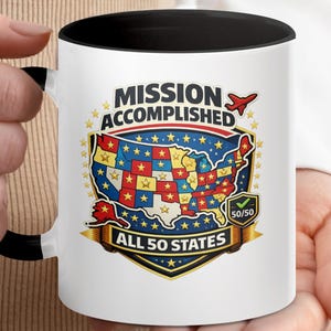 May include: White ceramic mug with a black interior and handle. The mug features a colorful graphic of the United States map with the text "MISSION ACCOMPLISHED ALL 50 STATES". The design includes stars and a red airplane.