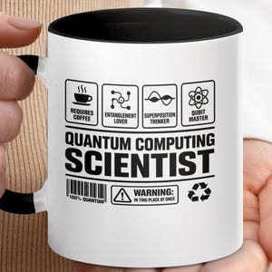 May include: A white ceramic mug with a black handle and the text "But First, Coffee" in a black, bold font. The mug is sitting on a wooden surface. The mug is 4 inches tall.