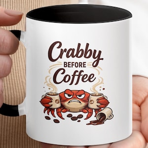 May include: A white ceramic mug with a black handle and the text "But First, Coffee" in a black, bold font. The mug is on a white surface. The mug is approximately 4 inches tall.