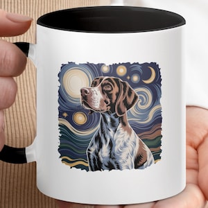 Op de afbeelding: Witte keramische mok met een zwarte binnenkant en handvat. De mok heeft een kleurrijke illustratie van een hond met een bruin-witte vacht, tegen een achtergrond van een sterrenhemel. De hond is het middelpunt van het ontwerp.