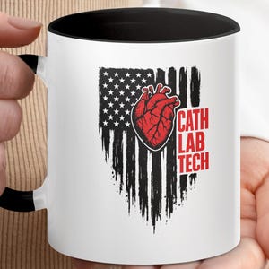 May include: White ceramic mug with a black interior and handle. The mug features a distressed American flag design with a red anatomical heart and the words "CATH LAB TECH" in red.