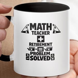 May include: White ceramic mug with a black interior and handle, featuring the text "MATH TEACHER RETIREMENT PROBLEM SOLVED" in black. The mug is held by a person.