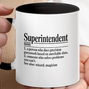 Puede incluir: Taza de cerámica blanca con interior y asa negros. La taza presenta la palabra "Superintendent" en negrita negra, junto con una definición. La definición describe con humor el rol, incluyendo las frases "conjeturas de precisión" y "resuelve problemas que no puedes".