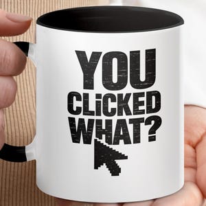 May include: A white ceramic mug with a black interior and handle. The front features the black text "YOU CLICKED WHAT?" in a bold, distressed sans-serif font, positioned above a black pixelated computer mouse cursor icon.