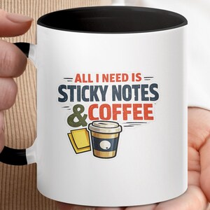 May include: White ceramic mug with a black interior and handle. The mug features the text "ALL I NEED IS STICKY NOTES & COFFEE" in a colorful design, along with illustrations of sticky notes and a coffee cup.