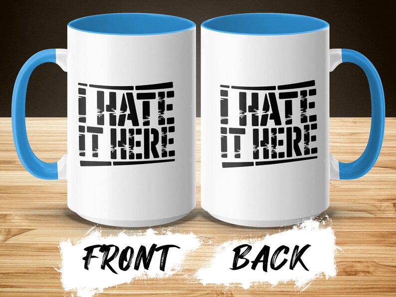 White mugs with blue handles, showing "I HATE IT HERE" text on front and back.