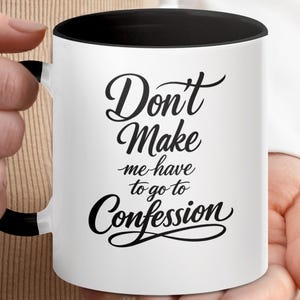 May include: White ceramic mug with a black interior and handle. The mug features the phrase "Don't Make me have to go to Confession" in black script. The mug is held by a person.