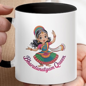 Może przedstawiać: Biały ceramiczny kubek z czarnym wnętrzem i uchwytem. Kubek przedstawia kreskówkową ilustrację tancerki Bharatanatyam w kolorowym tradycyjnym stroju. Tekst "Bharatanatyam Queen" jest napisany stylizowaną czcionką.