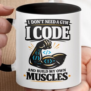 May include: White coffee mug with a black interior and handle. The mug features the text "I DON'T NEED A GYM I CODE AND BUILD MY OWN MUSCLES" with a graphic of a flexing arm with code symbols.
