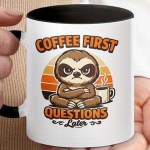 Puede incluir: Una taza de cerámica blanca con un asa negra y el texto "But First, Coffee" en negrita negra. La taza está llena de un líquido oscuro, probablemente café, y se encuentra sobre una superficie de color claro.