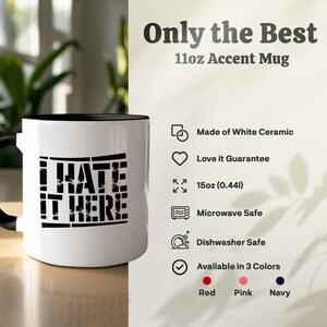 White ceramic accent mug with "I hate it here" text, dishwasher safe.