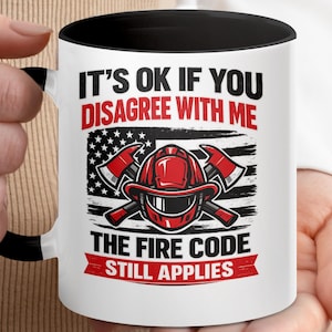 May include: White ceramic mug with a black interior and handle, featuring a firefighter's helmet and crossed axes design. The text reads "IT'S OK IF YOU DISAGREE WITH ME THE FIRE CODE STILL APPLIES" in red and black.