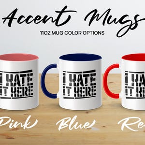 Three 11oz mugs with "I Hate It Here" text, in pink, blue, and red.