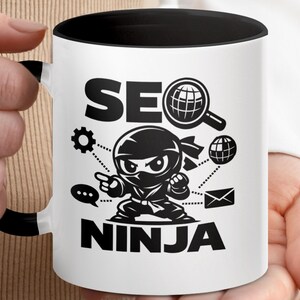 May include: White ceramic mug with a black interior and handle. The mug features the words "SEO NINJA" in bold black letters, along with a cartoon ninja character and SEO-related graphics like a magnifying glass over a globe and a gear.
