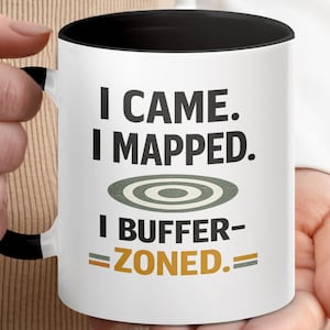 Peut inclure: Mug en céramique blanche avec intérieur et anse noirs. Le mug affiche le texte "I CAME. I MAPPED. I BUFFER-ZONED." en noir et or, avec un graphique de cible. Idéal pour les joueurs.