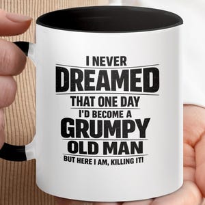 May include: A white ceramic mug with a black handle and interior rim. The front features black text that reads: I NEVER DREAMED THAT ONE DAY I'D BECOME A GRUMPY OLD MAN BUT HERE I AM, KILLING IT! The design uses a mix of bold and standard fonts.