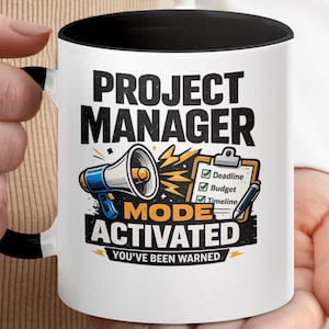 May include: White ceramic mug with a black interior and handle. The mug features the text "PROJECT MANAGER" above an illustration of a megaphone, clipboard, and lightning bolts. Below the illustration is the text "MODE ACTIVATED, YOU'VE BEEN WARNED."