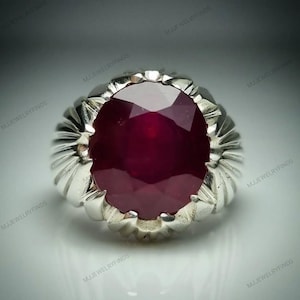 Op de afbeelding: Een zilveren ring met een grote, ovaal geslepen robijn. De robijn heeft een diepe, rode kleur en is gezet in een getextureerde, geribbelde zilveren band. De ring is een statement piece, geschikt voor speciale gelegenheden.