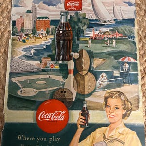 May include: Vintage Coca-Cola advertisement featuring a woman holding a bottle of Coke. The ad includes illustrations of various sports and leisure activities, with the text "Where you play" and "The pause that refreshes with ice-cold Coca-Cola."