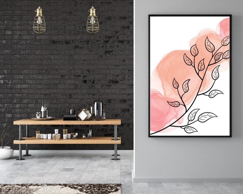 May include: A black framed print with a watercolor-style background in shades of pink and orange. A black line drawing of a branch with leaves is superimposed on the background.