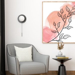 May include: A framed abstract art print with a black line drawing of a branch with leaves on a white background. The background has pink watercolor washes.