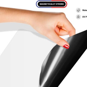 May include: A white magnetic sheet with a black magnetic backing. The sheet is being peeled back to reveal the black backing. The text "Magnetically Strong" is visible in red and blue.